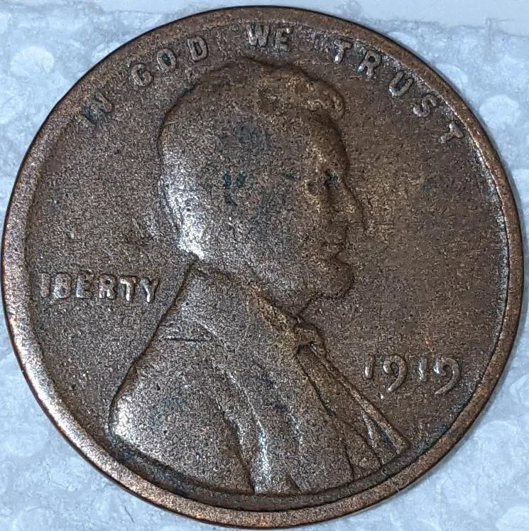 1919 Lincoln cent struck on Argentina 10 centavos foreign planchet showing silver-gray color compared to normal copper cent, with weight comparison on digital scale